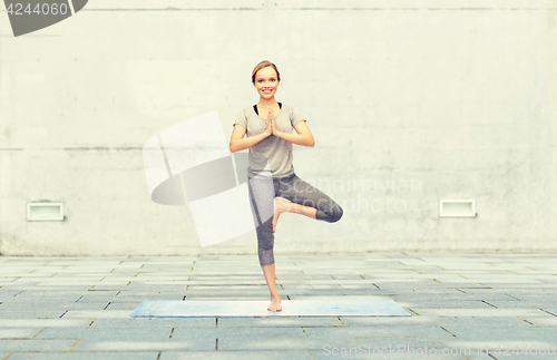 Image of woman making yoga in tree pose on mat