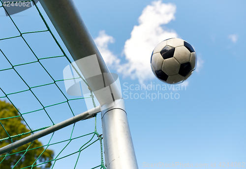 Image of soccer ball flying into football goal net over sky