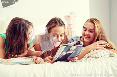 Image of friends or teen girls reading magazine at home