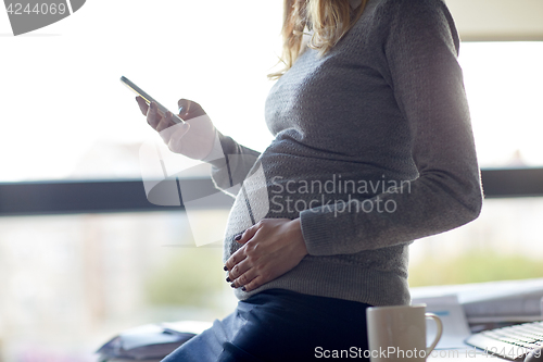 Image of pregnant businesswoman with smartphone at office