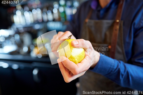 Image of bartender removing peel from lime at bar