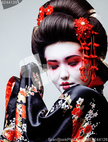 Image of young pretty geisha in black kimono among sakura, asian ethno close up