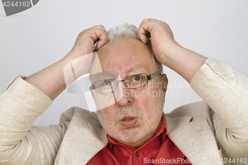 Image of White haired senior with glasses tearing his hair