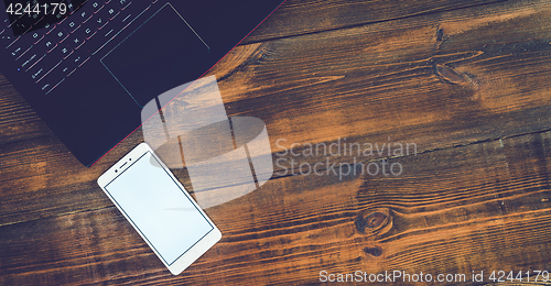 Image of Workspace with laptop and smartphone on hard wood desk