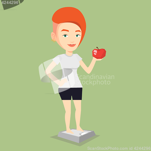 Image of Woman standing on scale and holding apple in hand.