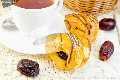 Image of Cookies with dates and tea in white cup on light board