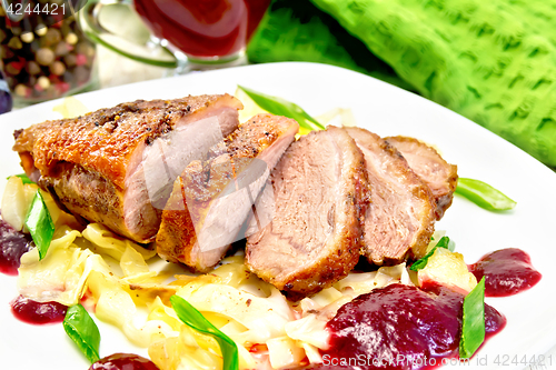 Image of Duck breast with plum sauce and cabbage in plate on light board