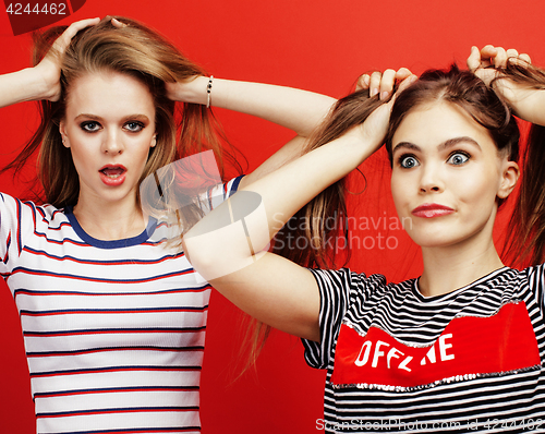 Image of two best friends teenage girls together having fun, posing emotional on red background, besties happy smiling, lifestyle people concept close up
