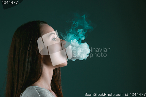 Image of The face of vaping young woman at black studio