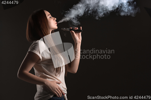 Image of The face of vaping young woman at black studio