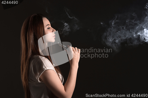 Image of The face of vaping young woman at black studio