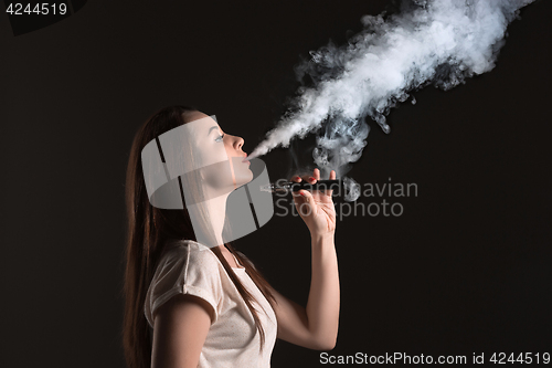 Image of The face of vaping young woman at black studio