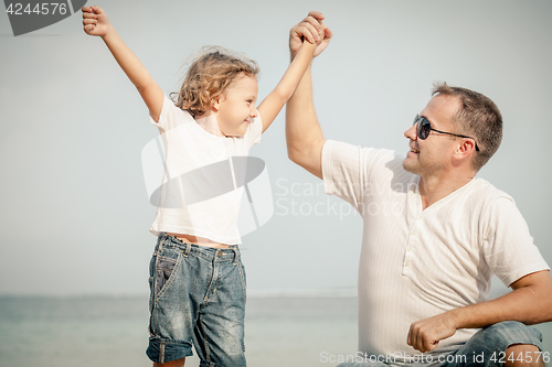 Image of Father and son playing on the beach at the day time.