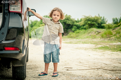 Image of little boy standing near the car