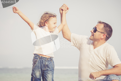 Image of Father and son playing on the beach at the day time.