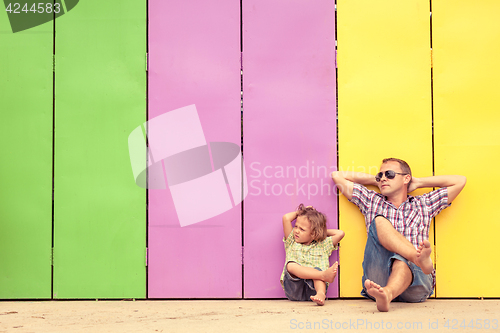 Image of Father and son relaxing near the house at the day time. 