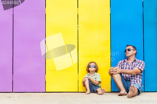 Image of Father and son relaxing near the house at the day time.