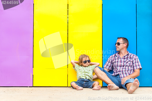 Image of Father and son relaxing near the house at the day time.