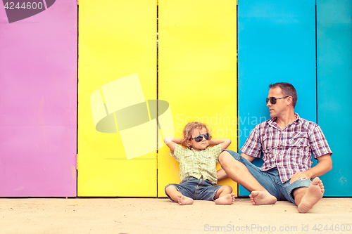 Image of Father and son relaxing near the house at the day time.