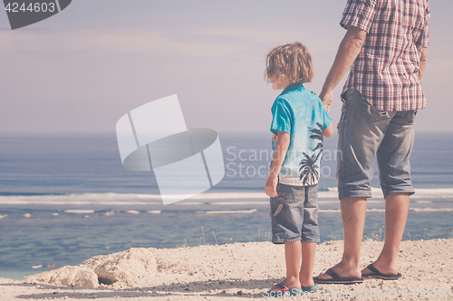 Image of Father and son playing on the beach at the day time.