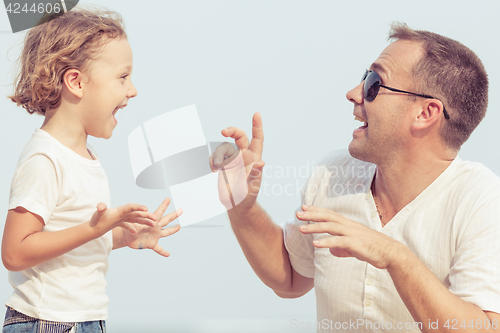 Image of Father and son playing on the beach at the day time.