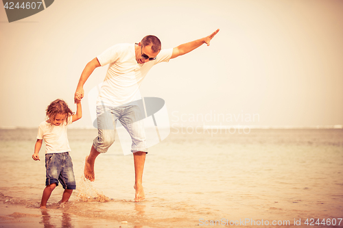 Image of Father and son playing on the beach at the day time.