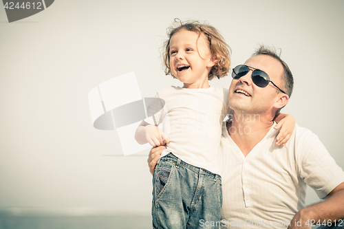 Image of Father and son playing on the beach at the day time.