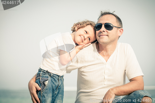 Image of Father and son playing on the beach at the day time.