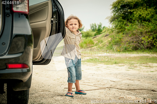 Image of little boy standing near the car