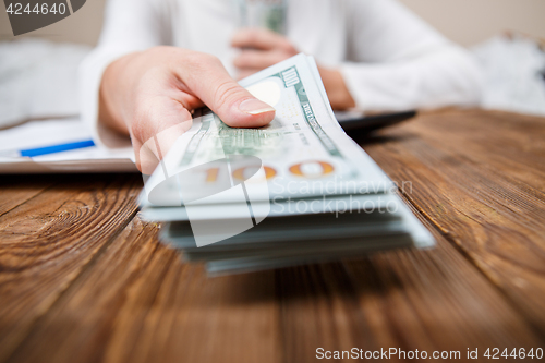 Image of Hands of person proposing money to you - closeup shot