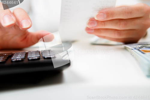 Image of savings, finances, economy and home concept - close up of hands with calculator counting money and making notes at home