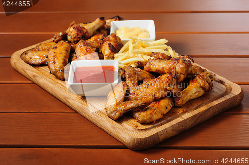 Image of Big wooden board with grilled chicken winds