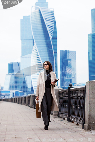 Image of Smiling beautiful woman in a light coat against the backdrop of 