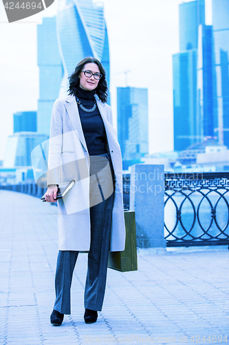 Image of Beautiful smiling woman in a light trendy coat on the waterfront