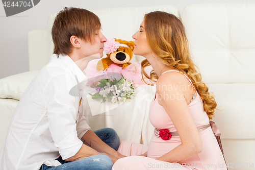 Image of young man and a pregnant woman kiss