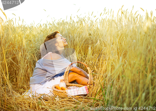 Image of Beautiful woman relaxes in a field among wheat ears