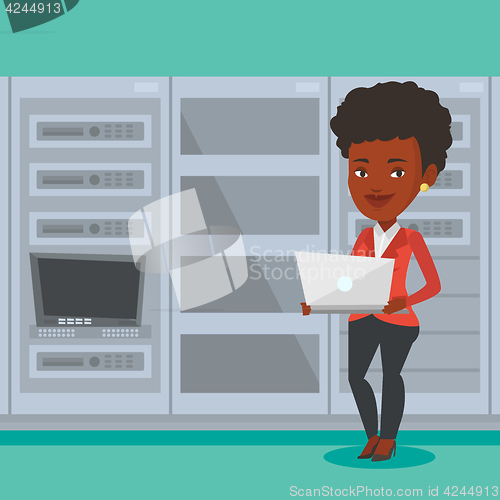 Image of Engineer working on laptop in network server room.