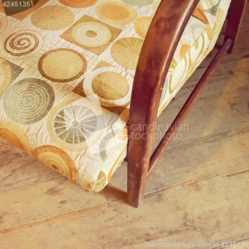 Image of Detail of a vintage textile armchair on wooden floor