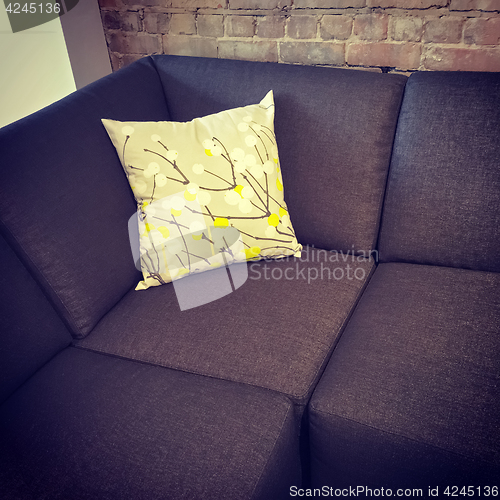 Image of Corner sofa with cushion near brick wall