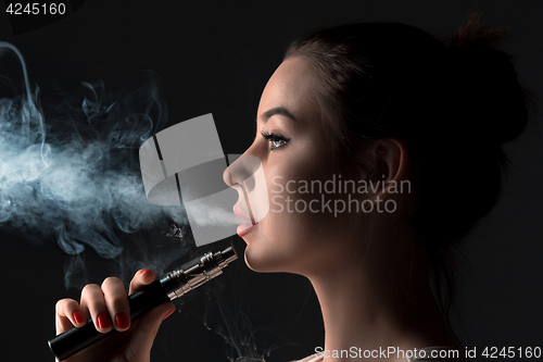 Image of The face of vaping young woman at black studio