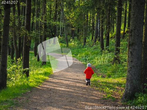 Image of Unrecognizable little boy in a big orange jacket running along o