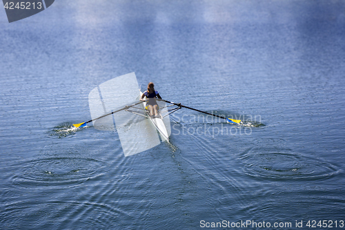 Image of Young woman rowing in boat on the lake