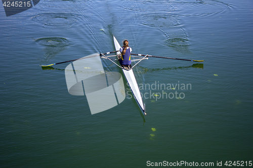 Image of Young woman rowing in boat on the lake