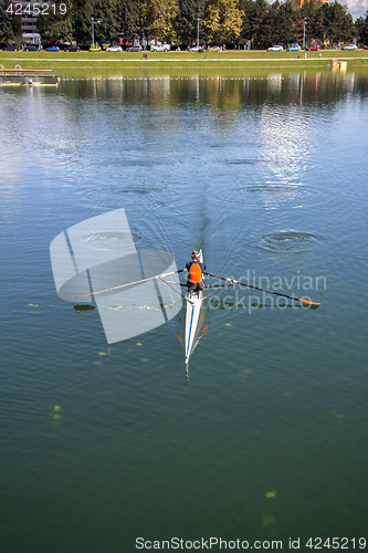 Image of Young woman rowing in boat on the lake