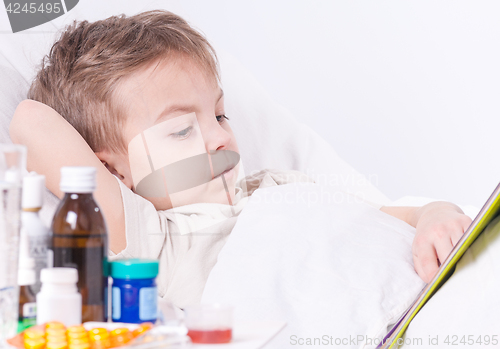 Image of Sick boy in bed reading book