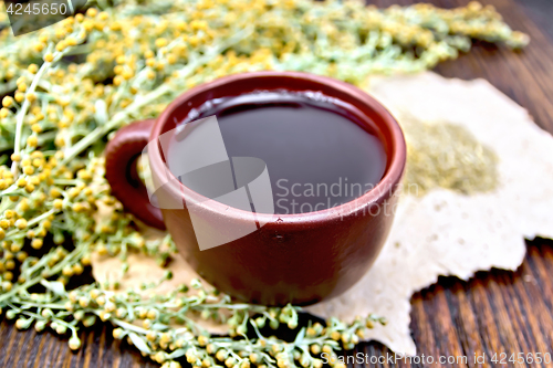 Image of Tea with wormwood in clay cup on paper