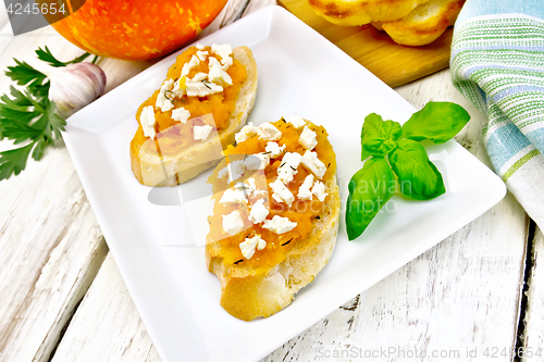 Image of Bruschetta with pumpkin and cheese in plate on board