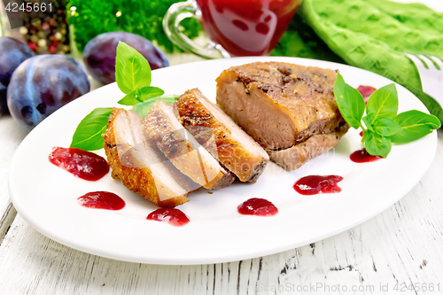Image of Duck breast with plum sauce and basil in plate on board
