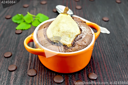 Image of Cake with chocolate and pear in red bowl on dark board