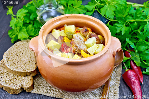 Image of Roast meat and squash in clay pot on dark board